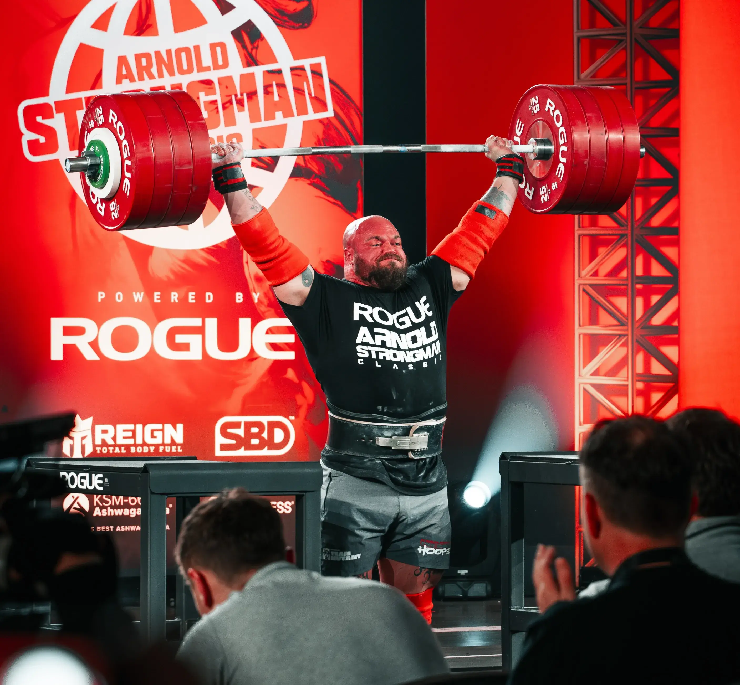 A strongman lifts a heavy barbell over his head during the Arnold Strongman Classic competition.