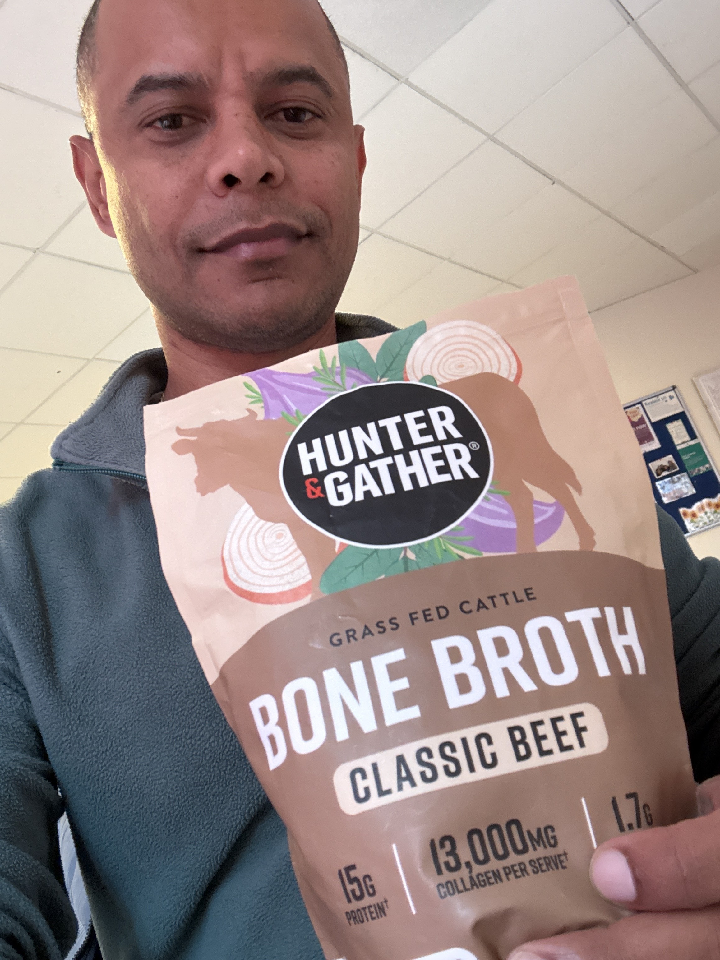A man in a fleece jacket holds a pouch of Hunter & Gather beef bone broth.