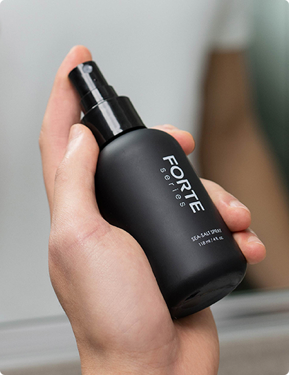 Hand holding a black spray bottle labeled 'FORTE series'.