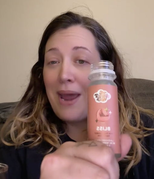 Person holding a bottle with the label 'Bliss' visible.