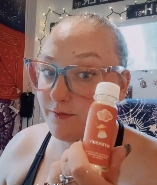 Person holding a small bottle with orange label in decorated room.