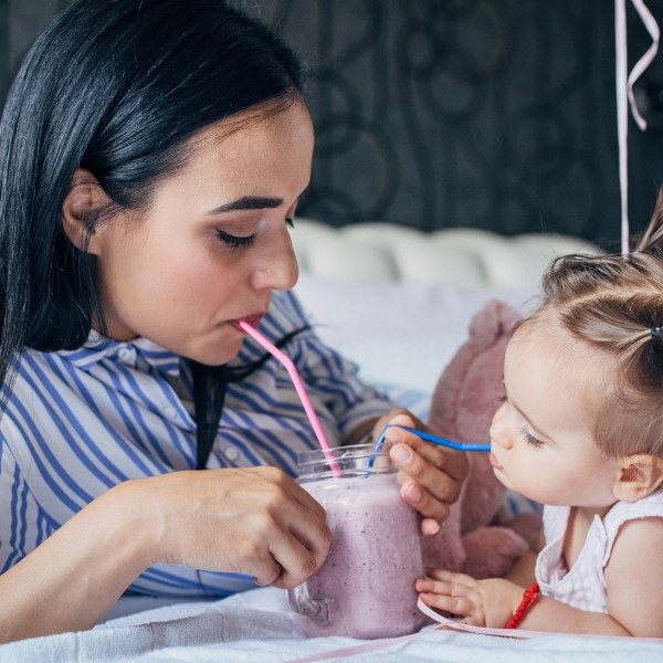 Woman and child drinking from a jar with straws.