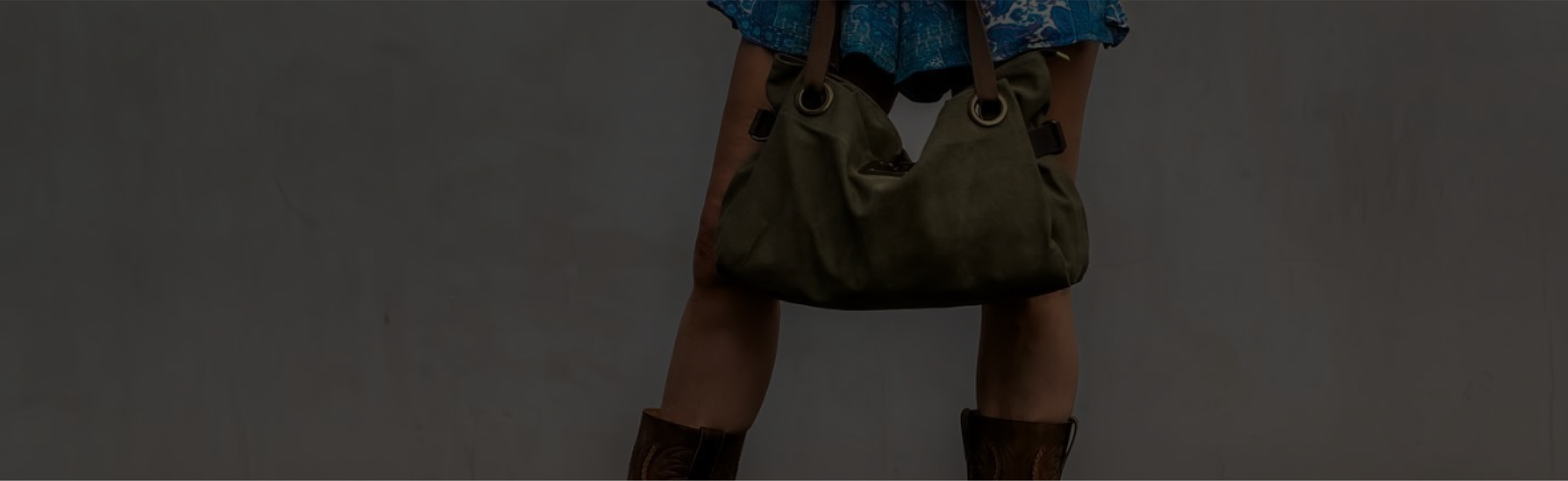 Person in blue skirt holding a green bag, wearing brown boots.