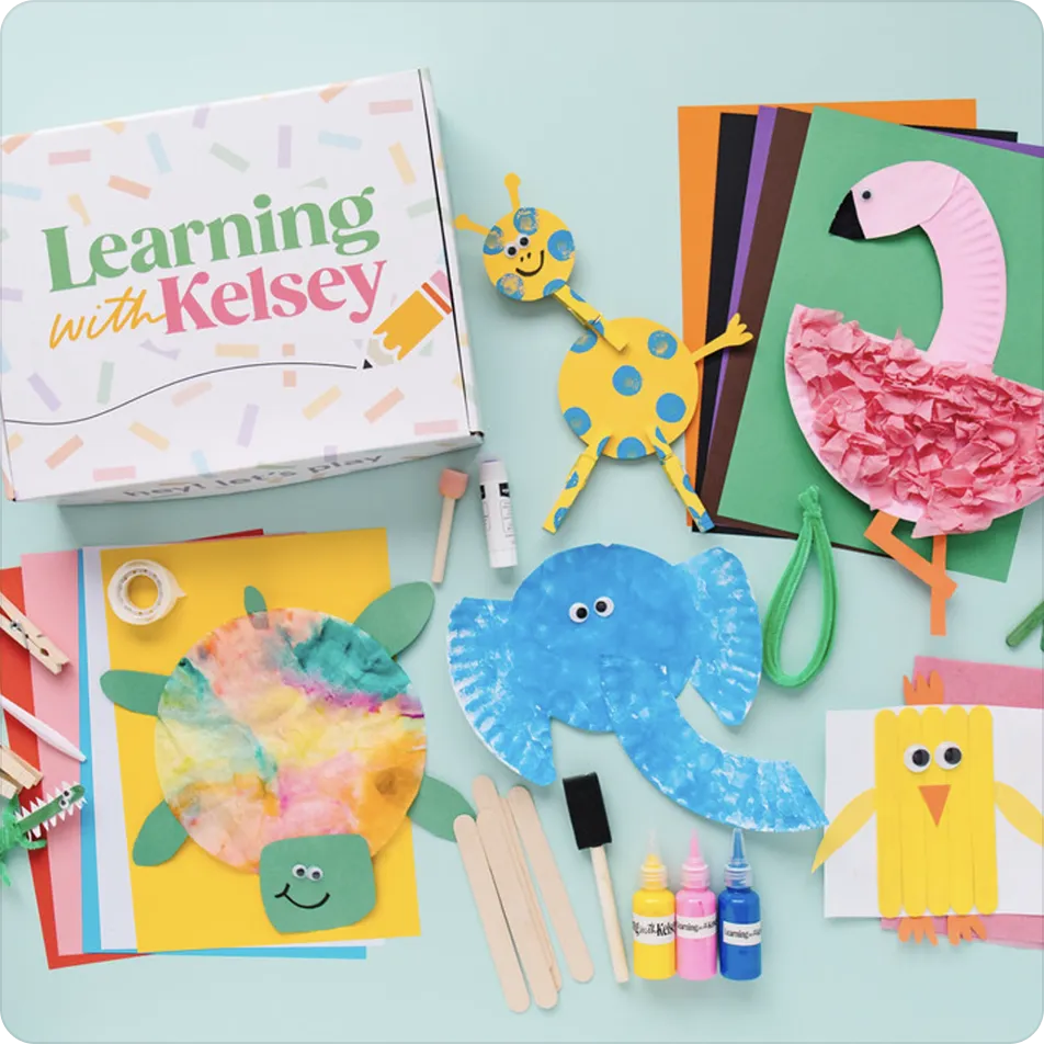 A 'Learning with Kelsey' craft box surrounded by colorful paper animal projects and art supplies.