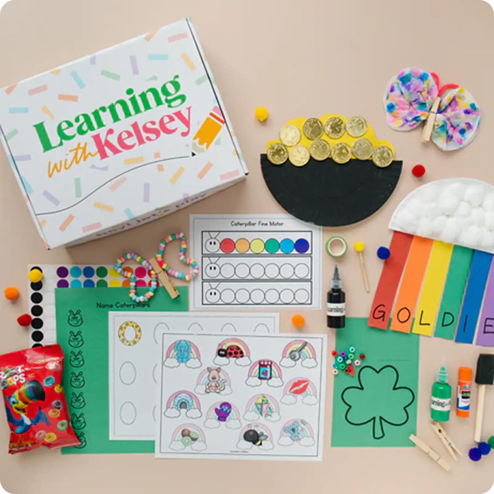 An overhead view of a 'Learning with Kelsey' box surrounded by various children's arts and crafts supplies.