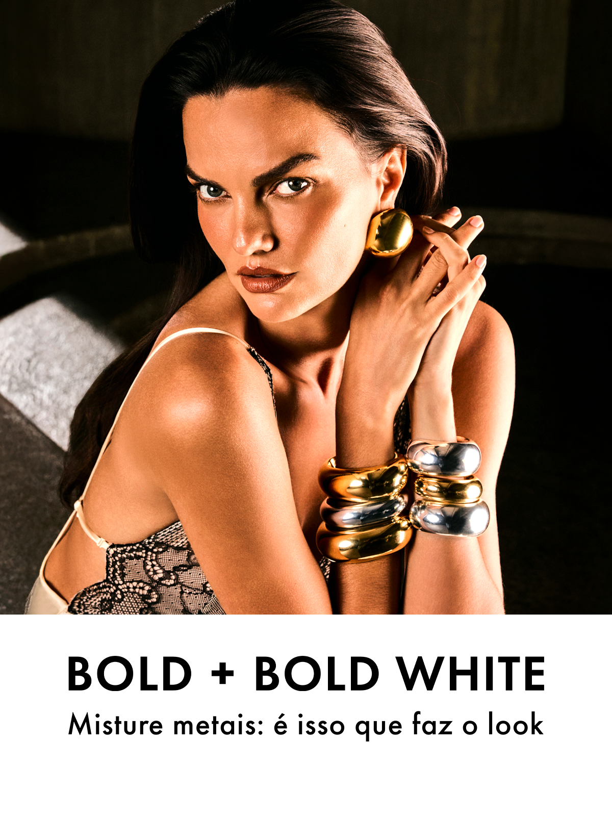 A woman with an intense gaze models a large gold earring and chunky gold and silver bracelets.