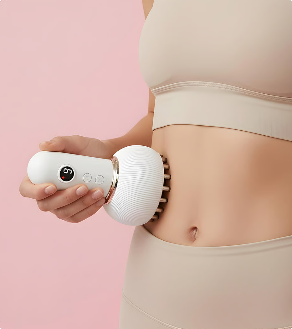 A person holds a white handheld electric massager against their abdomen against a pink background.
