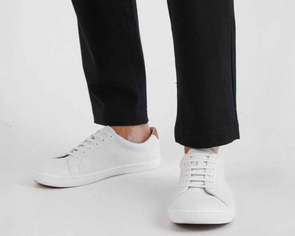 Person wearing white sneakers and black pants on a white background.