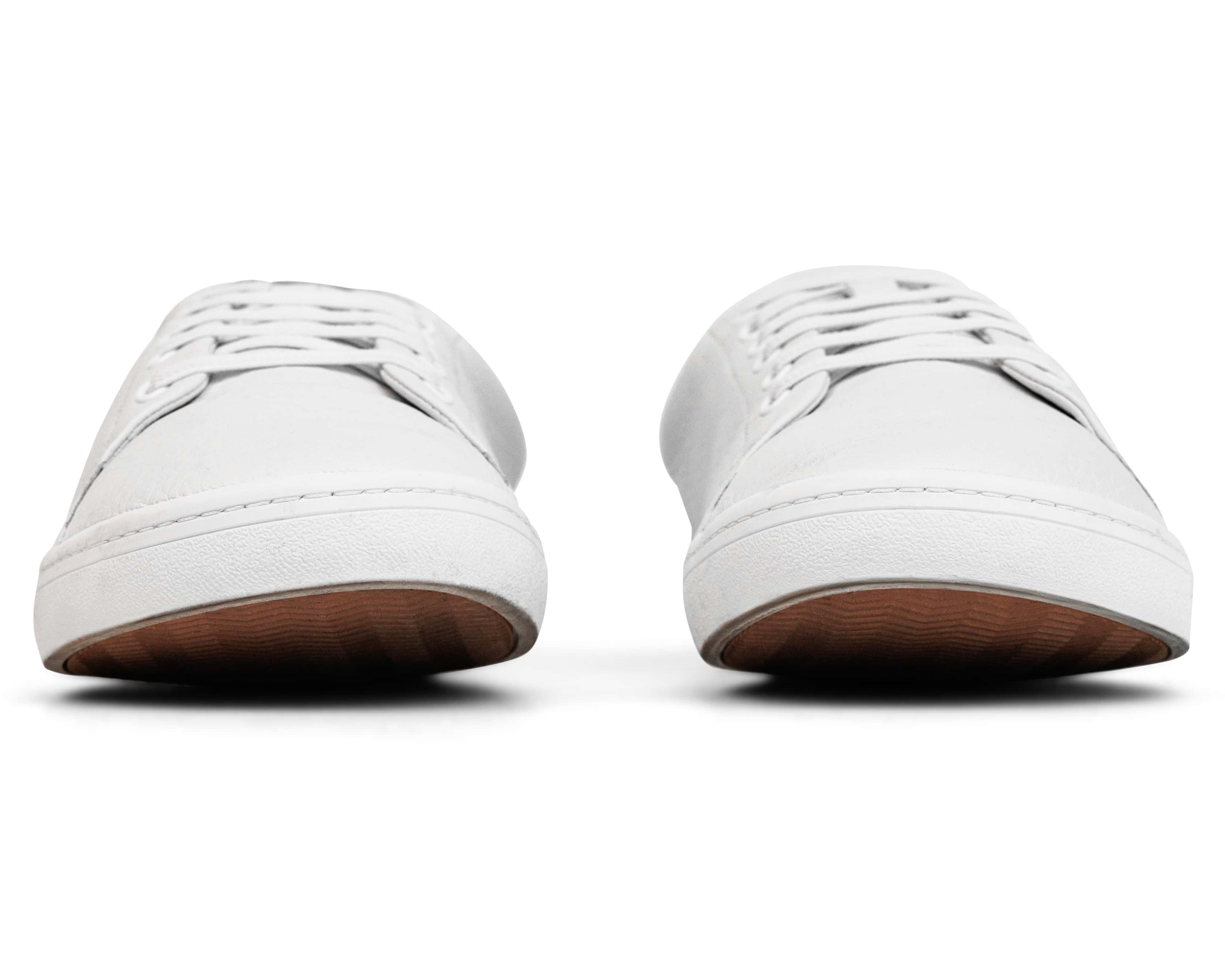 Pair of white sneakers with brown soles, viewed from the front.