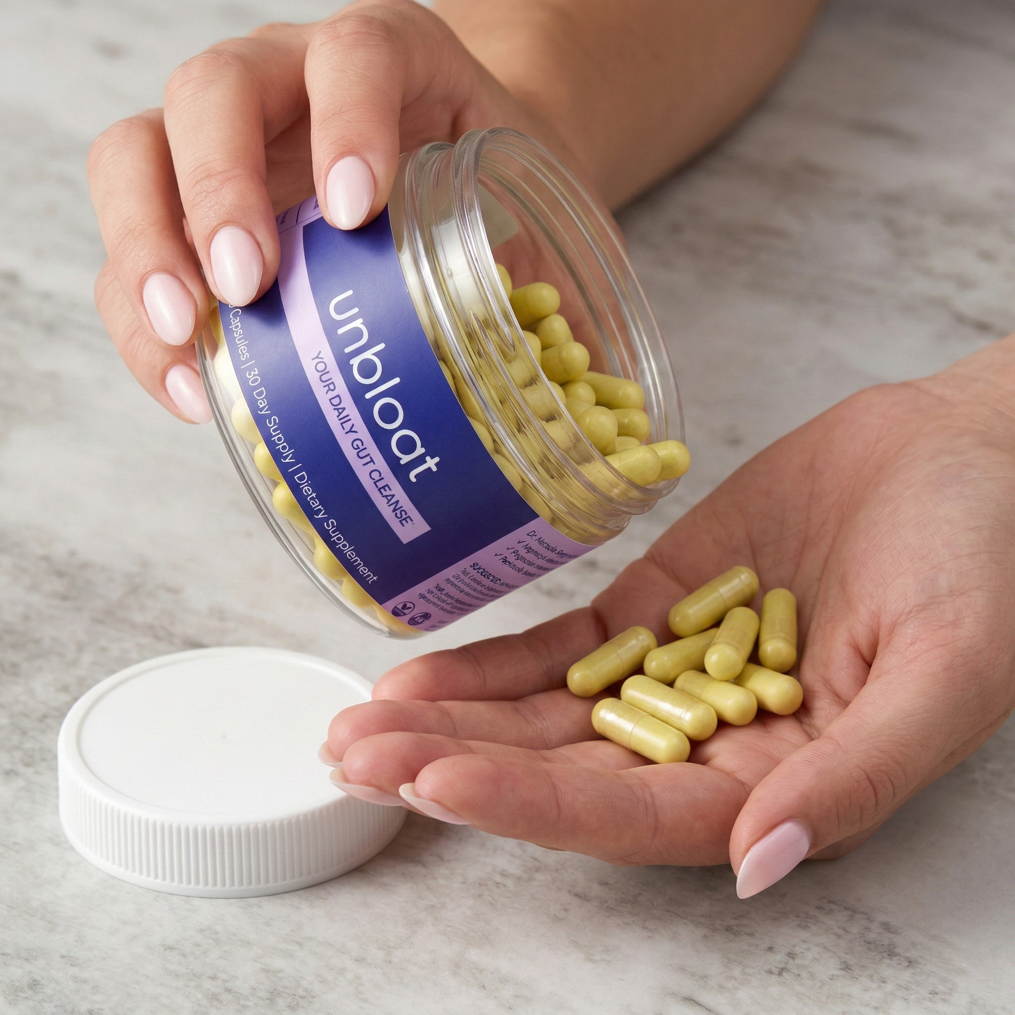 A person pouring yellow Unbloat dietary supplement capsules from a clear jar into their hand.