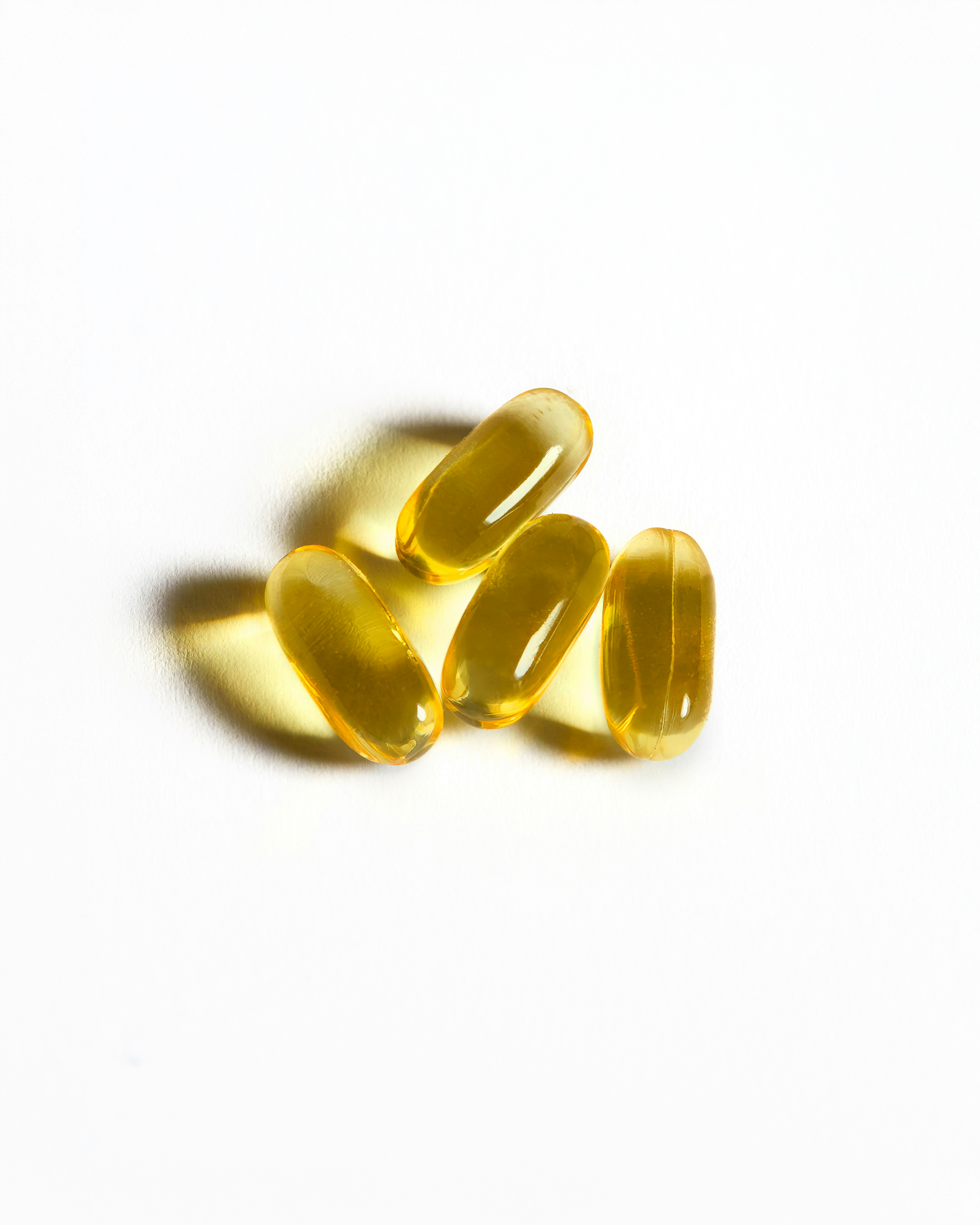 Four yellow gel capsules on a white background.