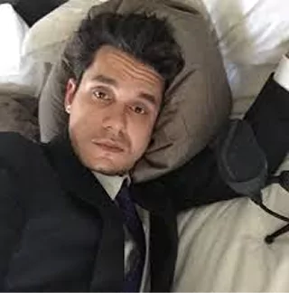 Person in a suit lying on a bed with a pillow.