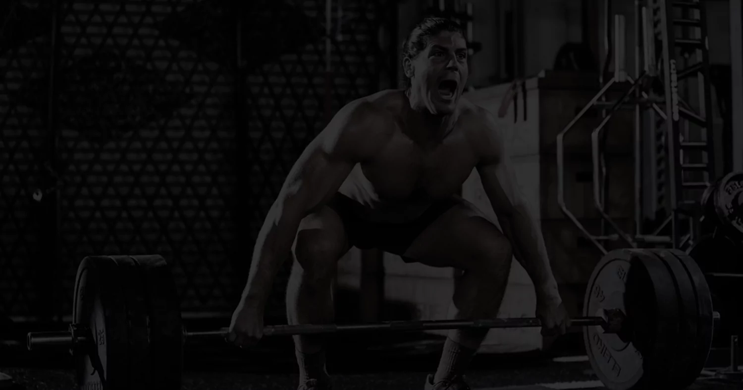 A man intensely lifting a barbell in a gym setting.